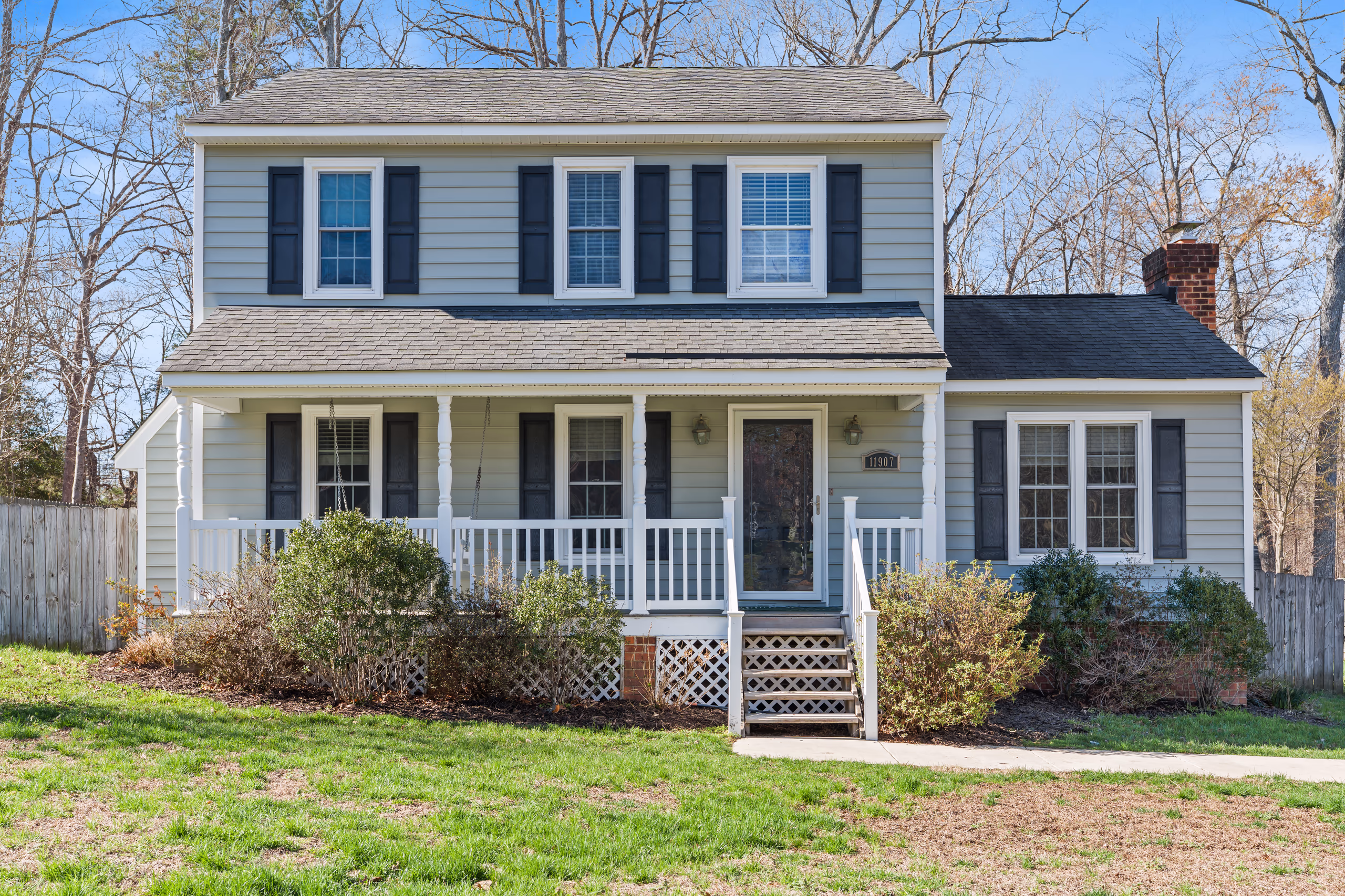 Two-story light blue house with a white porch and dark blue shutters
