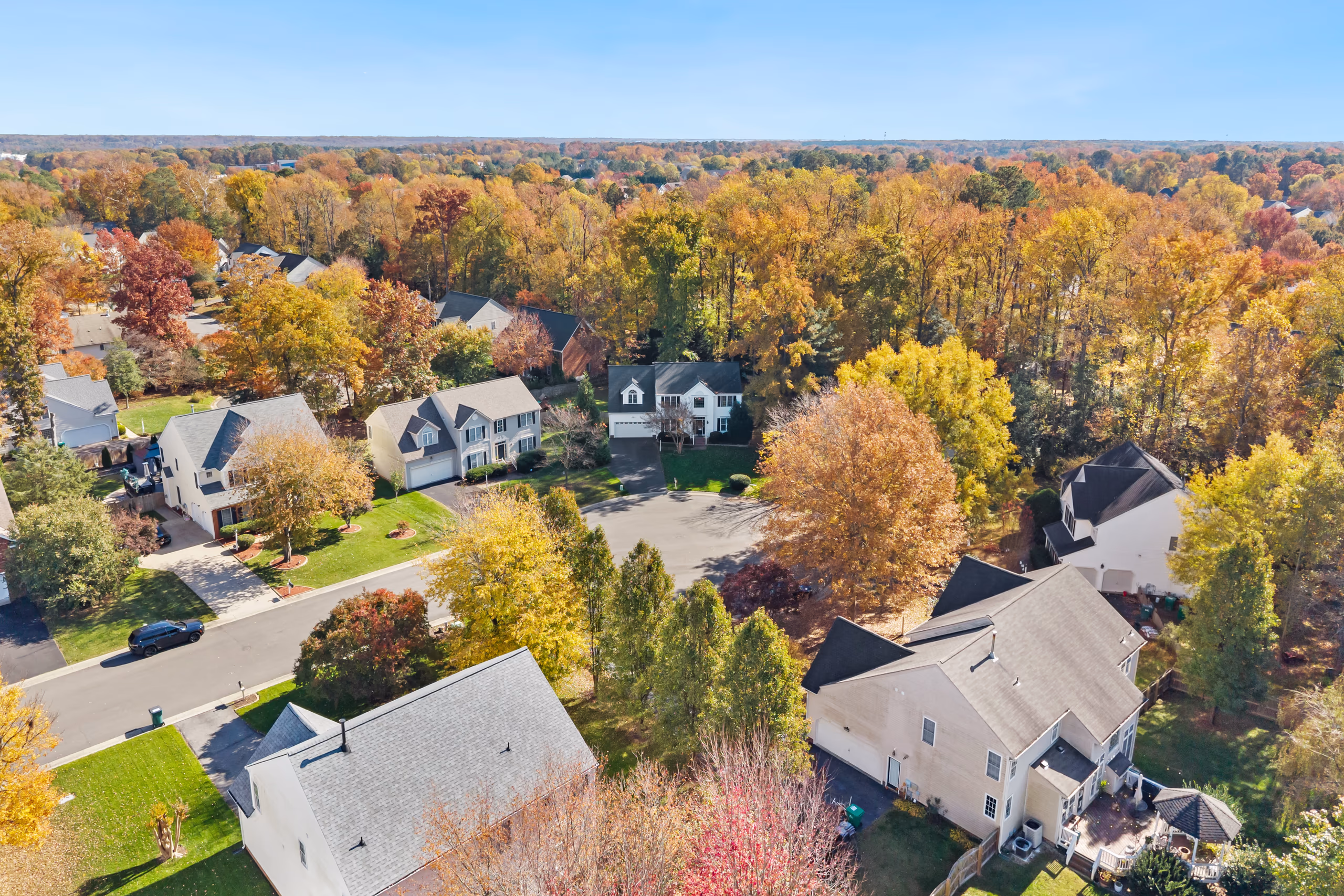 Aerial view of suburban homes in autumn, showcasing fall foliage and residential streets.